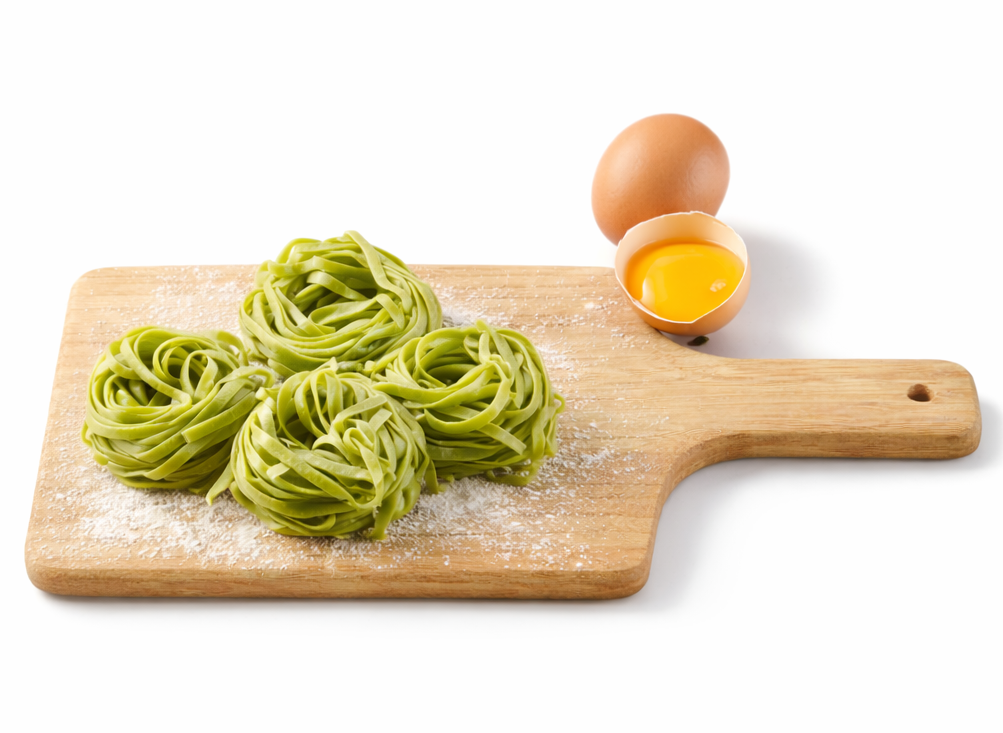 Quatre nids de tagliatelles vertes posés sur une planche en bois